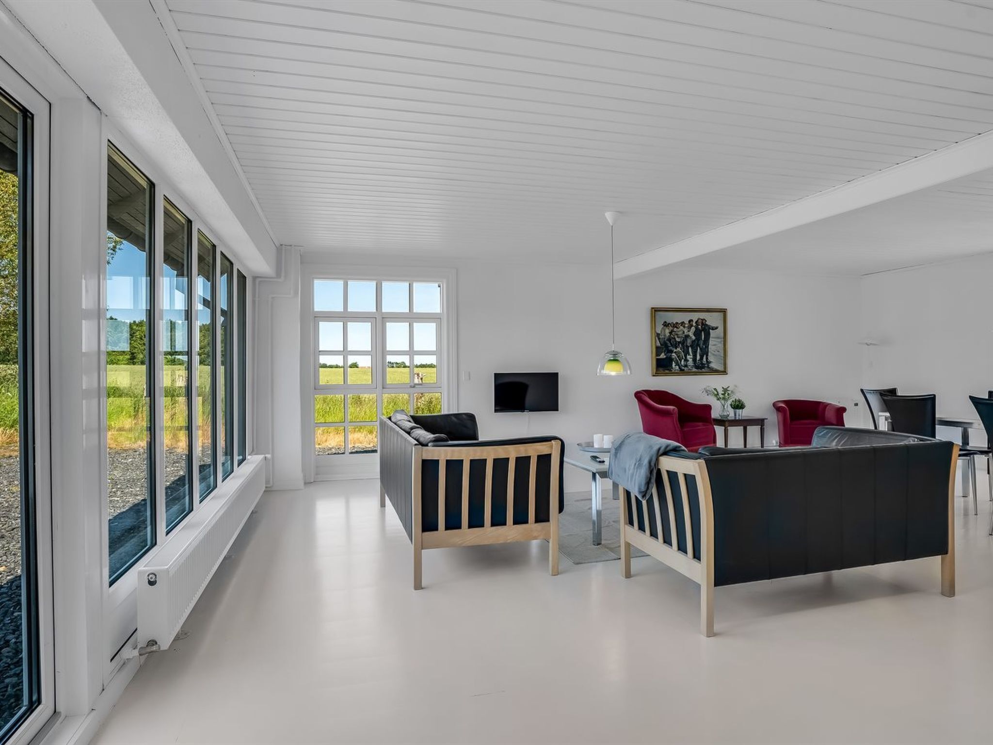A modern room with large windows, a flat-screen TV, and a red chair.
