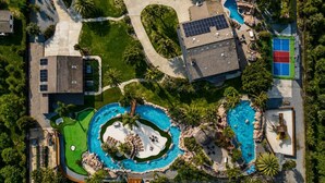 Vista aerea di una proprietà residenziale con due piscine, un campo da tennis, un pannello solare e un giardino curato.