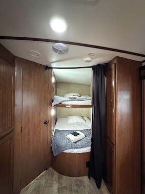A compact room with a bunk bed, wooden wardrobe, and a ceiling light.