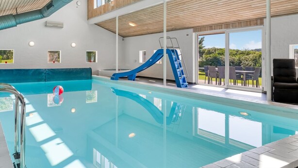 An indoor swimming pool with a blue slide, a sunroof, and a view of the outdoors. - "Maris" - 20km from the sea by Interhome (Østervrå)