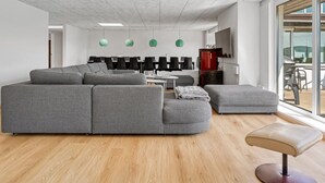 A modern office space with a large grey sectional sofa, a small round table, and a bench. - "Maris" - 20km from the sea by Interhome (Østervrå)