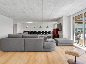 Ein moderner Büroraum mit einem großen, grauen Ecksofa, einem kleinen runden Tisch und einer Bank.