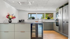 A modern kitchen with a central island, built-in appliances, and a window with a view. - "Maris" - 20km from the sea by Interhome (Østervrå)