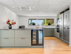 Eine moderne Küche mit einer zentralen Kochinsel, integrierten Geräten und einem Fenster mit Blick.