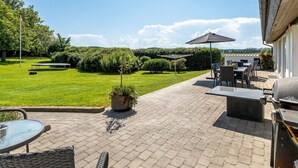 A patio area with outdoor furniture, a barbecue grill, and a view of a well-maintained lawn and trees. - "Maris" - 20km from the sea by Interhome (Østervrå)