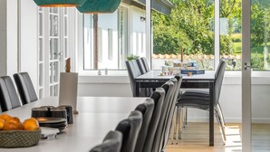 A modern dining area with a long table, chairs, and a view of greenery outside. - "Maris" - 20km from the sea by Interhome (Østervrå)