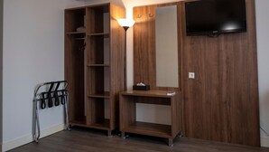 A room with a wooden wardrobe, a TV mounted on the wall, and a ceiling-mounted air conditioner.