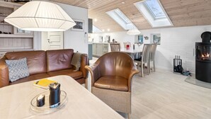 Uma sala de estar moderna com sofá de couro, mesa de jantar, lareira e claraboias.