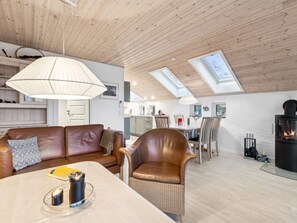 Ein modernes Wohnzimmer mit Ledersofa, Esstisch, Kamin und Dachfenstern.