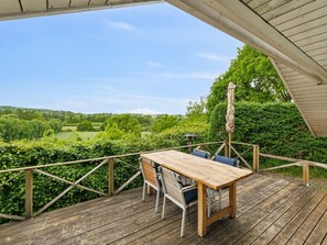 Eine Holzterrasse mit Tisch und Stühlen, mit Blick auf eine grüne Landschaft.