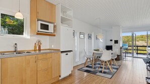 Een moderne keuken met houten kastjes, een magnetron en een eethoek met een tafel en stoelen.