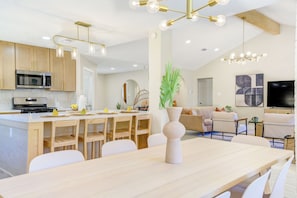 Une cuisine moderne avec des meubles en bois, un four à micro-ondes encastré et un coin repas comprenant une grande table et des chaises.