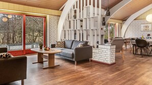 A modern interior with a wooden ceiling, a fireplace, a dining area, and a large window with a view of trees. - "Stilla" - 19km from the sea by Interhome (Østervrå)