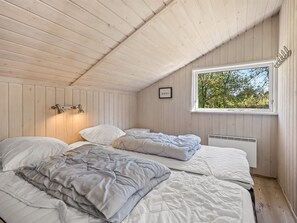 Ein Zimmer mit zwei Betten, einem Fenster mit Blick auf Bäume, einer Wandleuchte und einem gerahmten Bild.