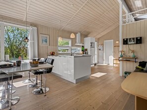 Eine moderne Küche mit einer zentralen Kochinsel, Holzböden und einem Essbereich mit Barhocker.
