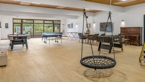 Ett rymligt inomhusområde med ett bordtennisbord, ett fotbollsspel och en hängande gungstol.