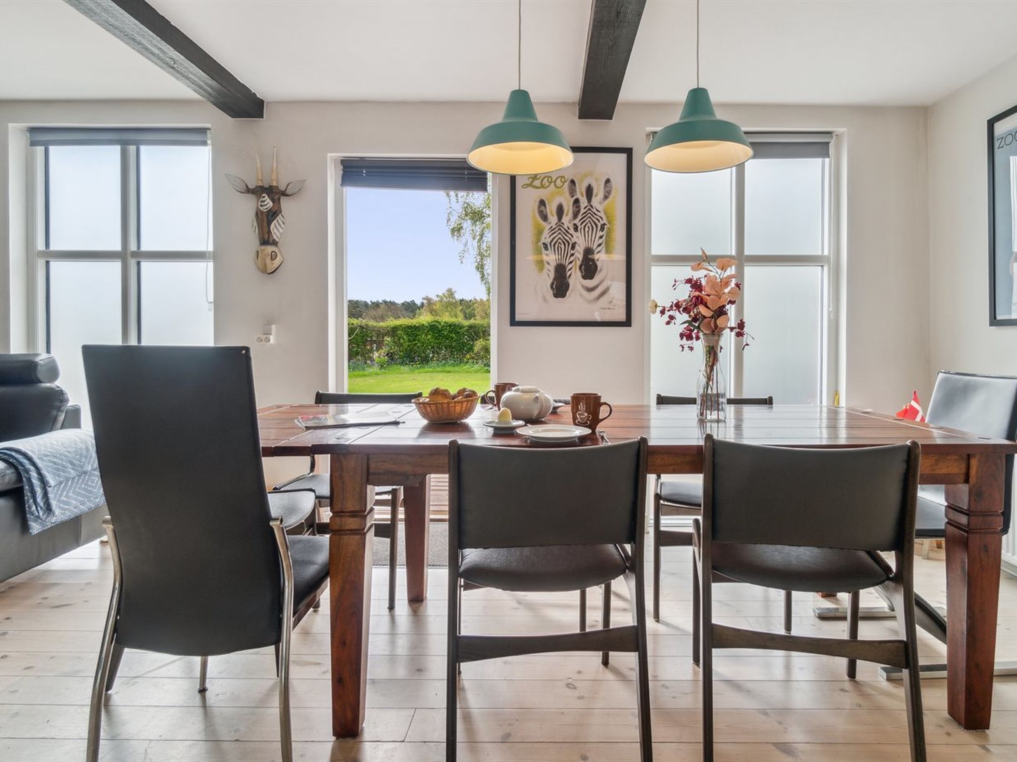 A dining area with a wooden table, chairs, and pendant lights.