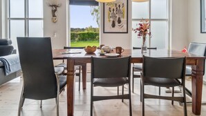 Un comedor con mesa de madera, sillas y lámparas colgantes.