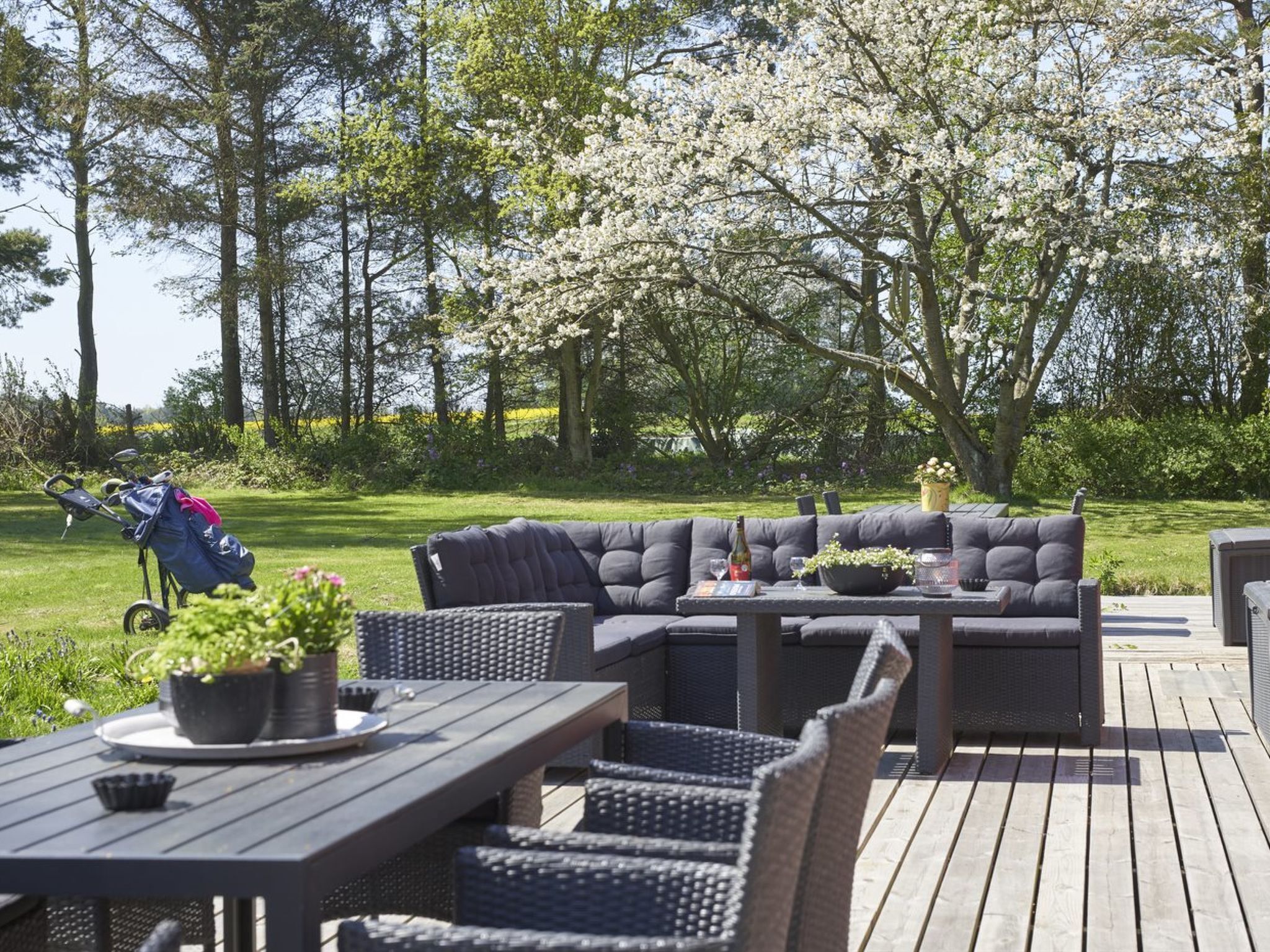 An outdoor patio with a dark-colored sofa, wicker chairs, and a table.