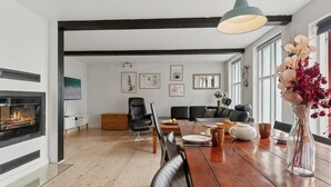 Una sala moderna con chimenea, comedor y sofás de cuero negro.