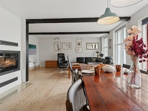Ein modernes Wohnzimmer mit Kamin, Essbereich und schwarzen Ledersofas.