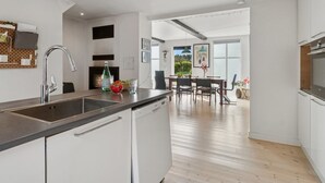 Una cocina moderna con lavavajillas integrado, un ventanal grande y un comedor con mesa y sillas.