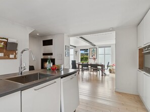 Eine moderne Küche mit Geschirrspüler, großem Fenster und Essbereich mit Tisch und Stühlen.
