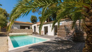 Ein Pool mit Holzterrasse, einer Steinmauer und einem Gebäude mit Ziegeldach.