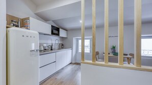 Una cucina moderna con mobili bianchi, un frigorifero bianco e pavimento in legno.