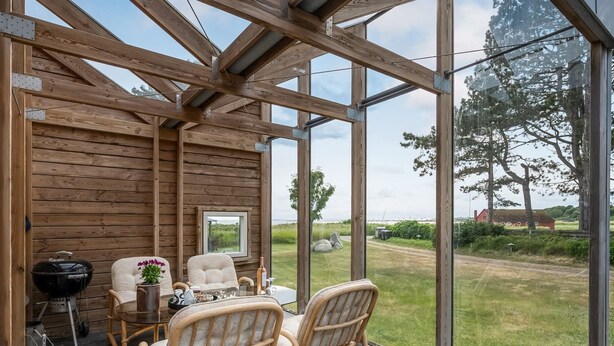 Une cabane en bois dotée d’un toit en verre, de meubles en osier et offrant une vue sur l’extérieur.