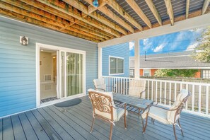 A covered porch with a wooden ceiling, a sliding glass door, and a table with chairs.
