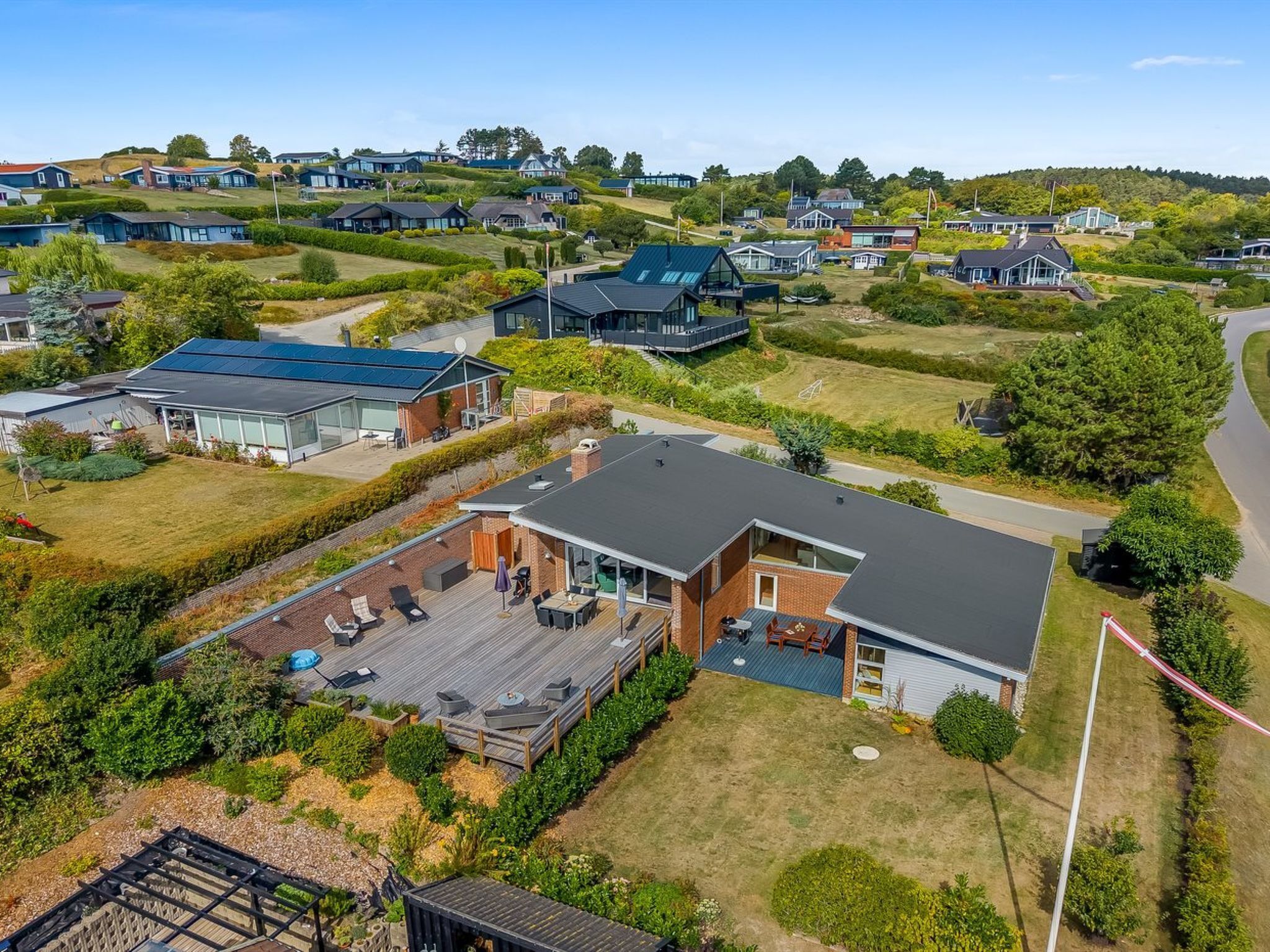 A residential area with modern houses, a well-maintained lawn, and a clear sky.