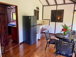 A compact kitchen with a refrigerator, a dining table with chairs, and a small island with a sink. - 2-bedroom apartment in a hotel accommodating 2 to 4 people (Ojochal)