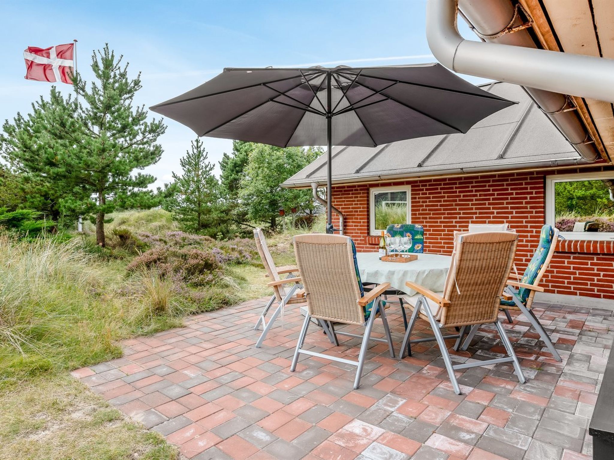 A patio with a table, chairs, and an umbrella.