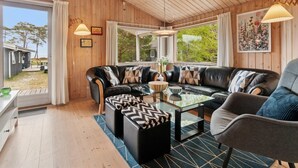 Ein gemütliches Wohnzimmer mit Ledersofa, Glastisch und Blick ins Freie.