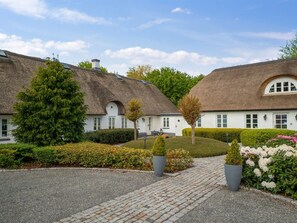 Ein Gebäude mit einem Strohdach, weißen Wänden und einem gepflasterten Weg zum Eingang.