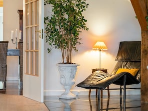Ein Zimmer mit einer großen Topfpflanze, einer Stehlampe, einer Lederbank und einem Korbstuhl.