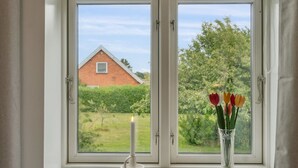Une fenêtre avec une bougie et un vase de tulipes.