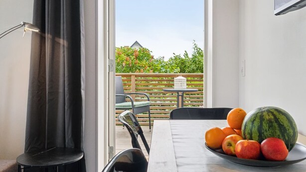 Une pièce comprenant une table, des chaises, un barbecue, une horloge et donnant sur un jardin.
