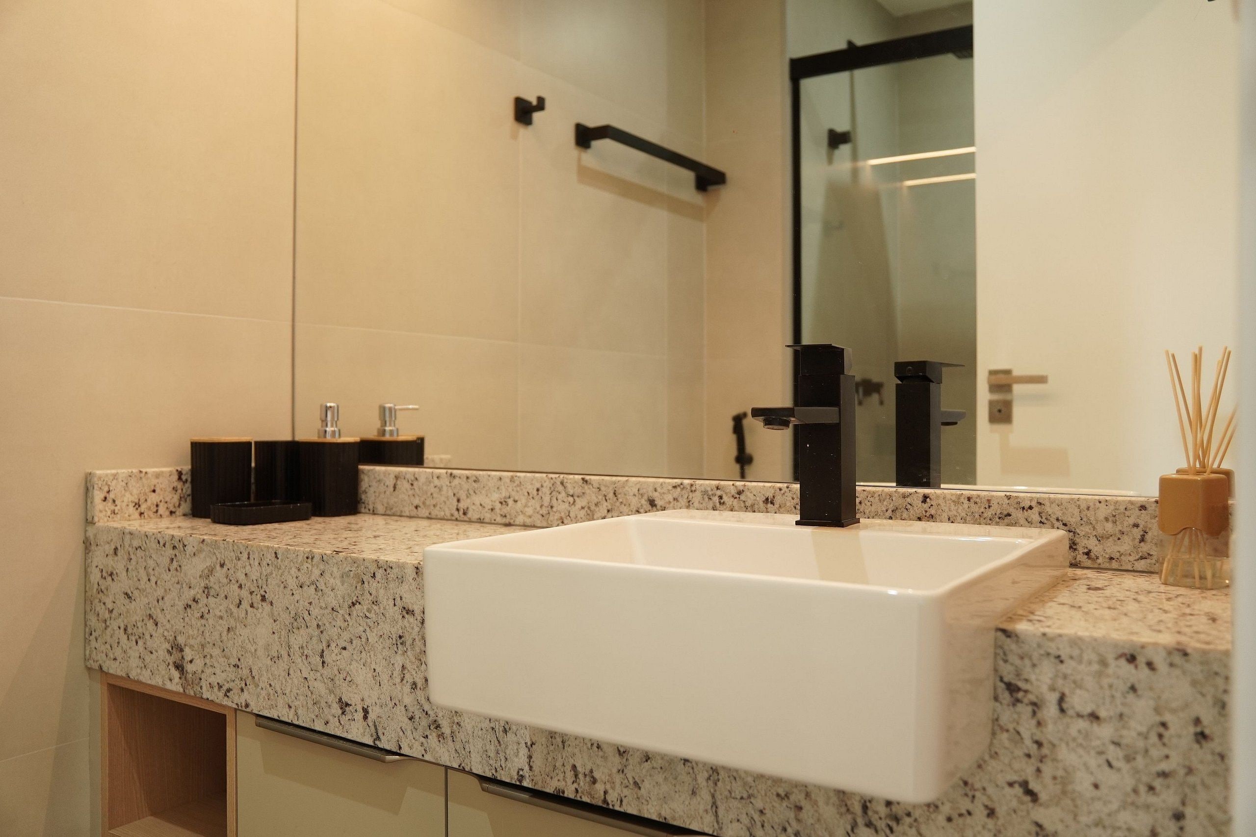 Une salle de bain moderne avec un lavabo blanc, un comptoir en granit et un grand miroir.