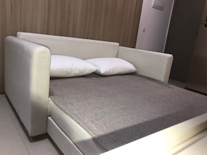 A modern, minimalist room with a grey sofa bed and two white pillows. - Beach Class Meireles by HostFácil (Fortaleza)