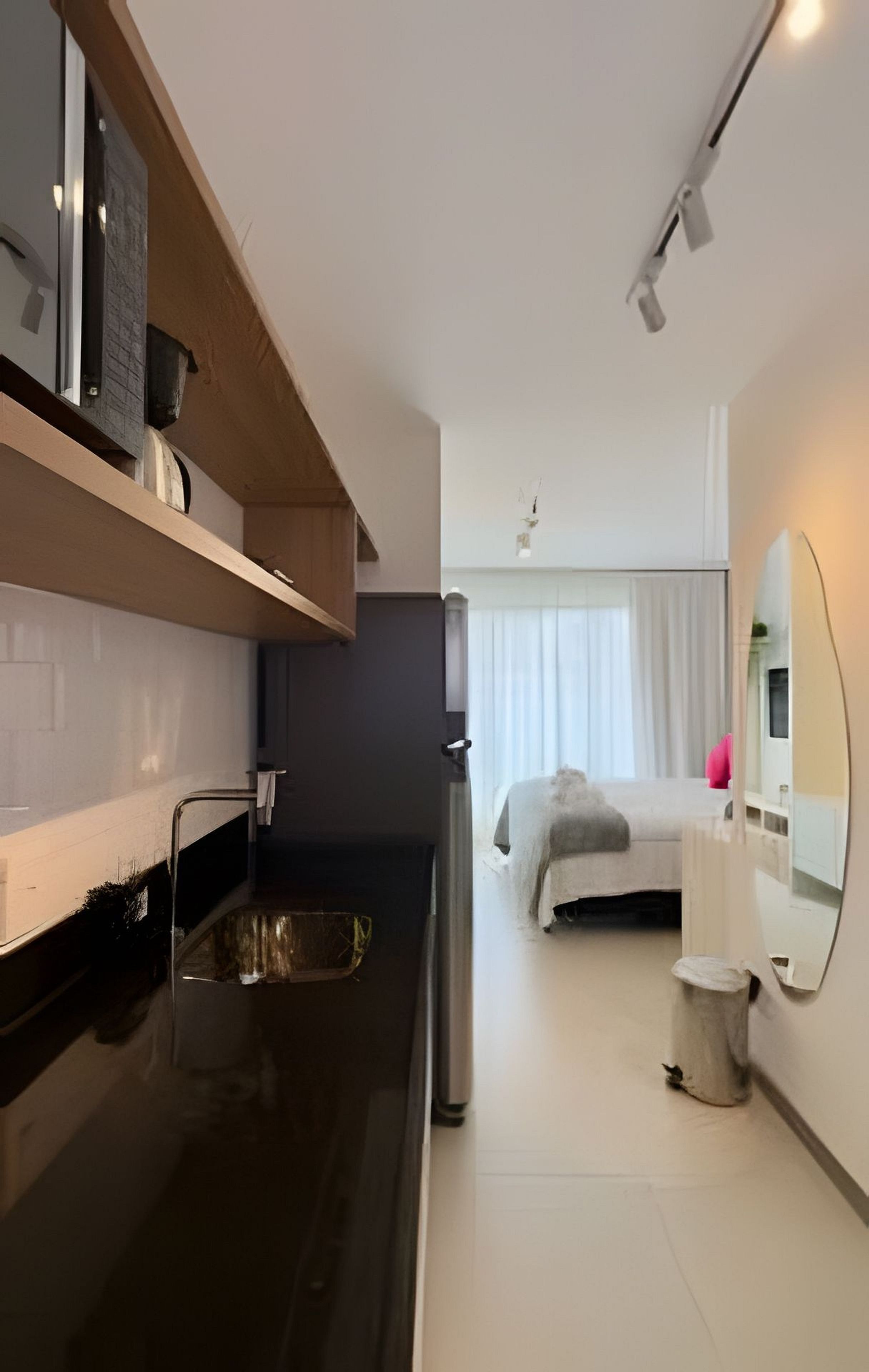 Una cocina moderna con encimera negra, pileta de acero inoxidable y estante de madera.