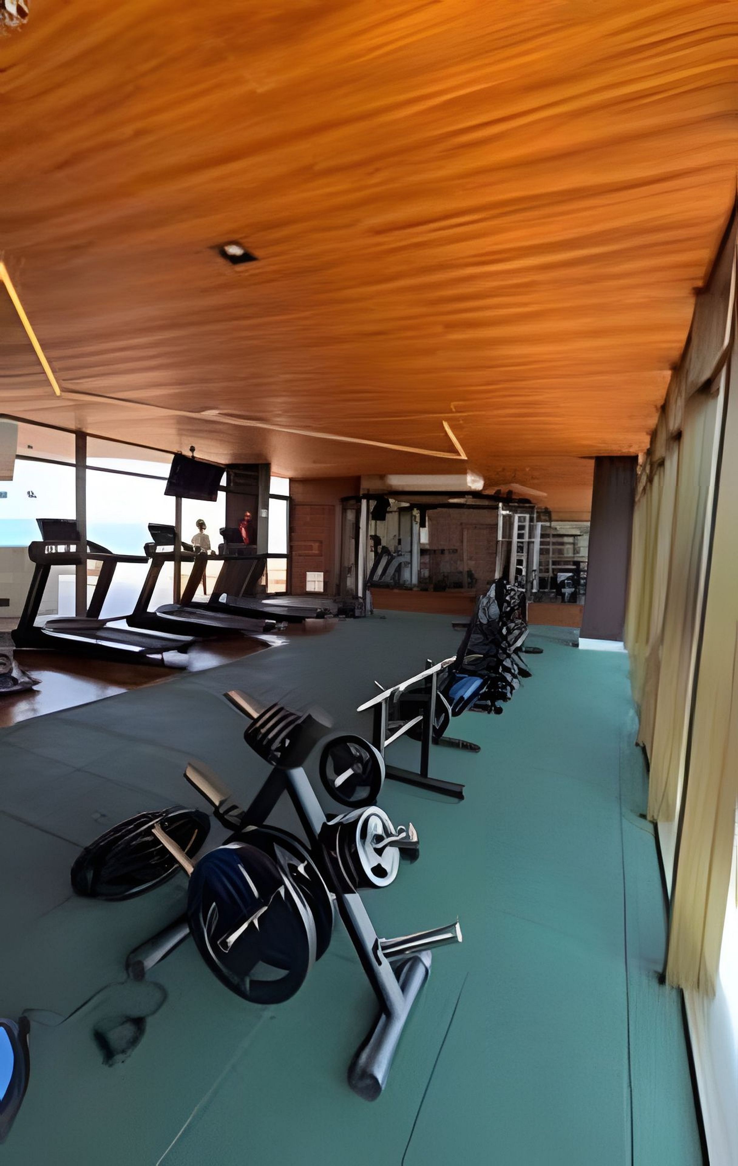 Un gimnasio con cintas de correr, equipamiento de levantamiento de pesas y un ventanal grande.