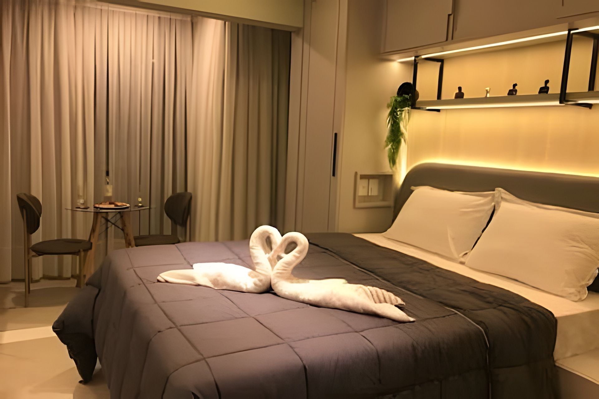 Ett hotellrum med en säng, ett litet bord, två stolar och en växt.