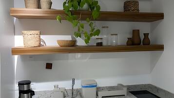 A kitchen with wooden shelves, a coffee maker, and a sink.
