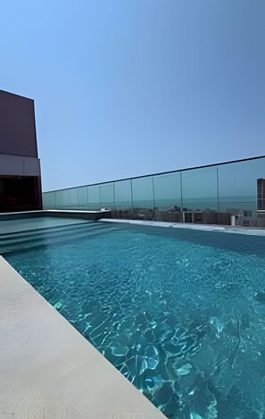 A rooftop pool with clear blue water, surrounded by a glass barrier and a modern building. - Beach Class Meireles by HostFácil (Fortaleza)