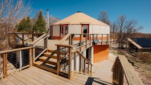 Una yurta con terraza de madera, una escalera y una antena parabólica.