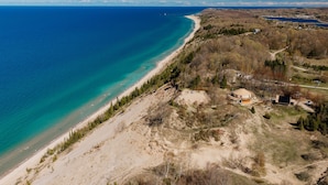 Vista aérea de una zona costera con una playa, un faro y un edificio circular.