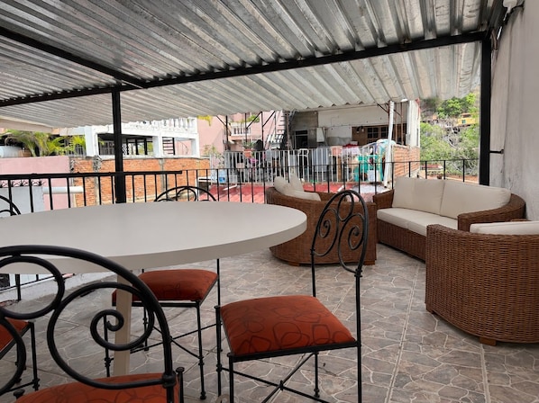 An outdoor patio with a round table and chairs, wicker sofas, and a metal railing. - Walkable Romantic Zone Studio • Near Beach • WiFi (Puerto Vallarta)