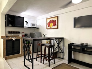 A compact kitchen with a microwave, refrigerator, and a painting of apples. - Walkable Romantic Zone Studio • Near Beach • WiFi (Puerto Vallarta)